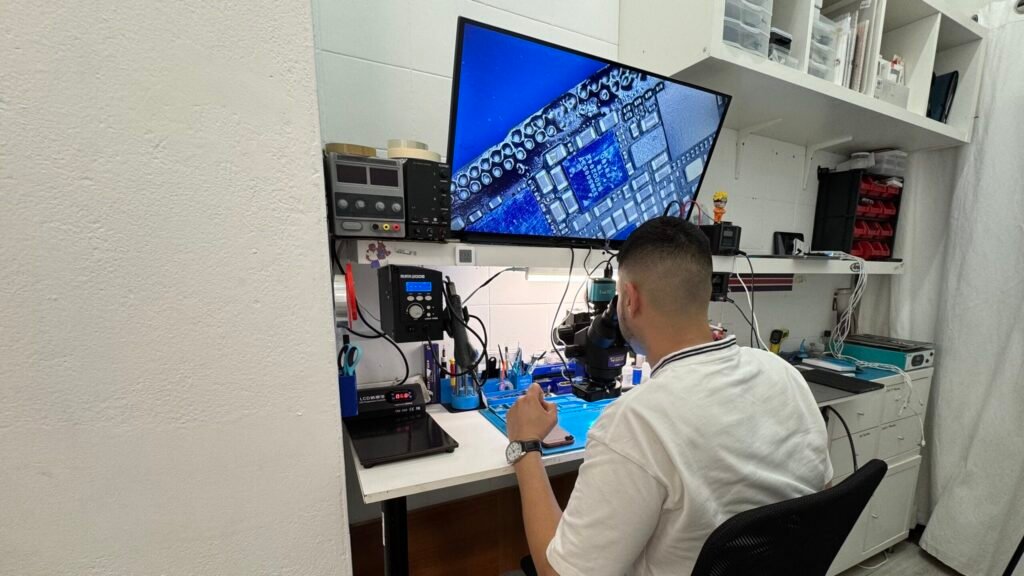 Técnico de Móvil Plus reparando una placa con microscopio