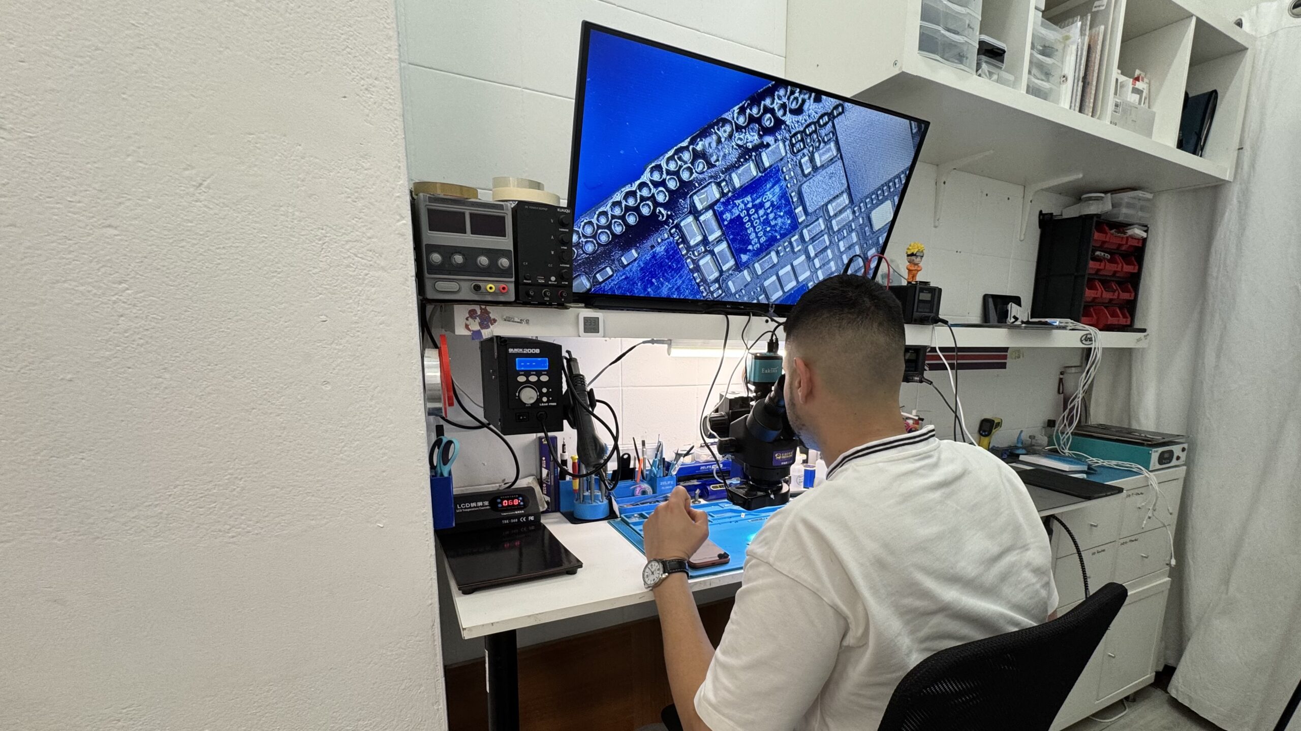 Técnico reparando placa base con microscopio profesional